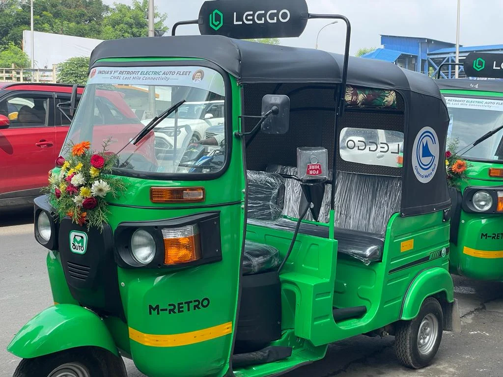A green Leggo electric auto with a flower garland, a Leggo roof sign and the Chennai Metro Rail logo