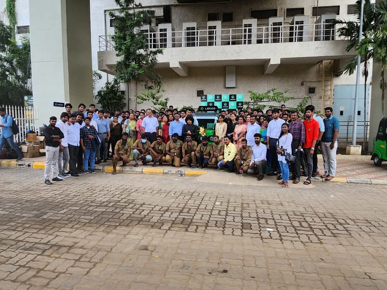 The Leggo team, drivers in uniform and guests in front of a Leggo auto and backdrop at a metro station