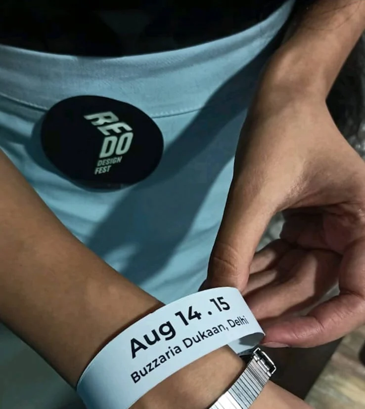 A REDO Design Fest badge and an entry wristband reading Aug 14-15, Buzzaria Dukaan, Delhi
